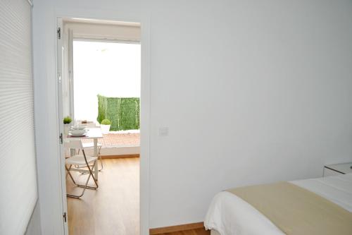 加的斯Ático Compañía的卧室拥有白色的墙壁,配有一张床和一张桌子