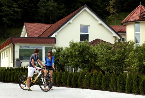 莫济列斯阔克康体公寓的男人和女人在房子前骑着自行车