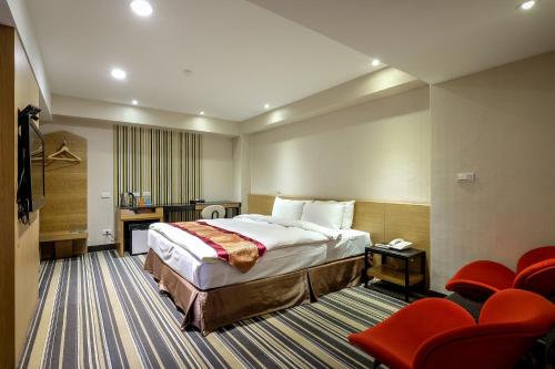 嘉义市国园商务大饭店的酒店客房,配有床铺和红色椅子