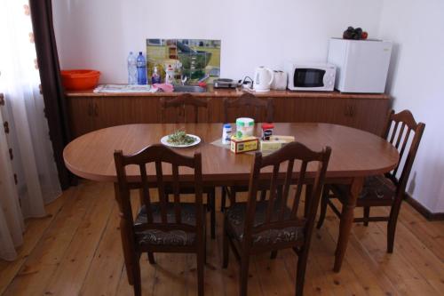 KhashuriGvirilas Sakhli Guest House的一张带椅子和桌子的木桌以及一间厨房