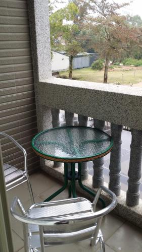 金宁乡爱玩客107的阳台上的玻璃桌和两把椅子