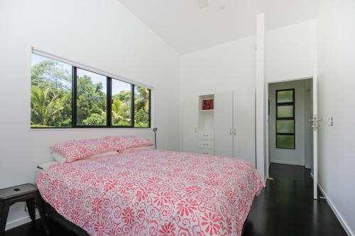 拉罗汤加Mata Manea的卧室配有粉红色的床和窗户。