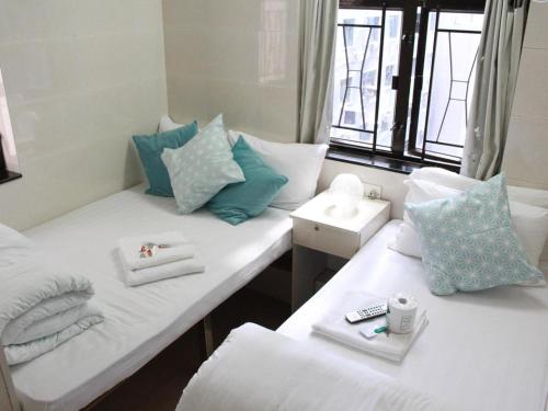 香港New Yan Yan Guest House reception 9th floor Flat E4 E6的配有白色和蓝色枕头的客房内的两张床