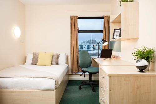 纽波特新港大学村公寓（校园住宿）的一间卧室配有一张床和一张带笔记本电脑的书桌