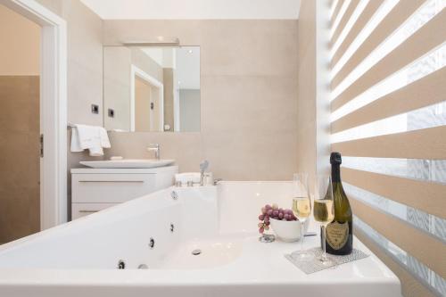 特罗吉尔Marina Baotić Apartments的白色浴室设有水槽和一瓶葡萄酒