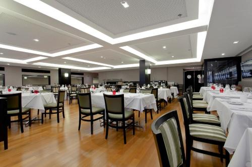 圣若泽杜斯坎普斯金色郁金香圣若泽杜斯坎普斯酒店的一间设有白色桌椅的用餐室