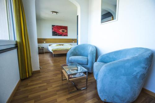 LʼAbbayeHÔTEL DE VILLE - La Baie Du Lac的客厅配有2把蓝色椅子和桌子