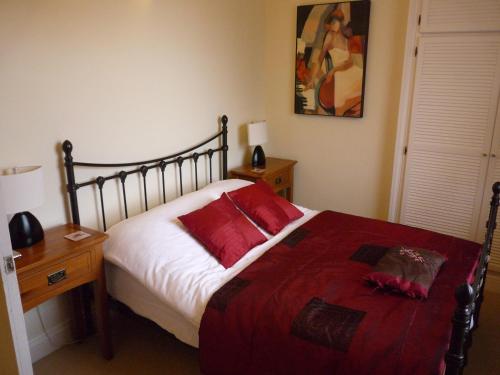 切尔滕纳姆帕拉贡服务式公寓的一间卧室配有一张带红色枕头的床