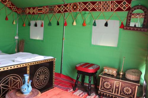 Fulayj al MashāʼikhLegend Desert camp的一间设有绿墙、桌子和凳子的房间