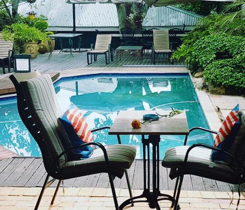 约翰内斯堡伊丽莎白庄园旅馆的游泳池前设有2把椅子和1张桌子