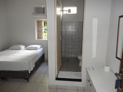 阿拉萨图巴阿拉萨图巴格兰德酒店的一间卧室配有一张床,浴室设有淋浴。