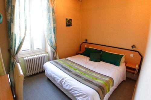 隆勒索涅甘贝塔酒店的一间卧室配有一张带绿色枕头的床和一扇窗户