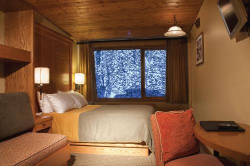 班夫阳光山峦旅舍的一间卧室设有一张床和一个大窗户