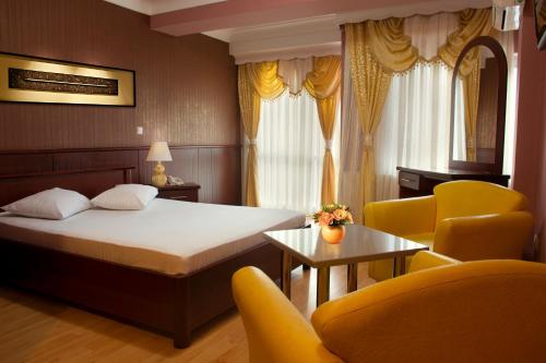佩奇King Hotel的酒店客房带一张床、一张桌子和椅子