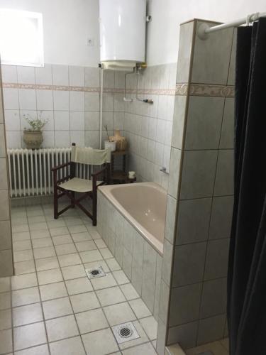 埃格尔Hív-Lak Apartman的带浴缸和椅子的浴室