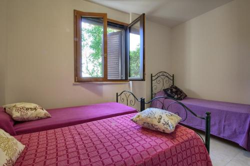 帕图Villetta Madrigale San Gregorio的一间卧室设有两张带紫色床单的床和窗户。