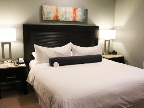 恩塞纳达港珊瑚码头酒店的一间卧室配有一张带两盏灯的大型白色床。