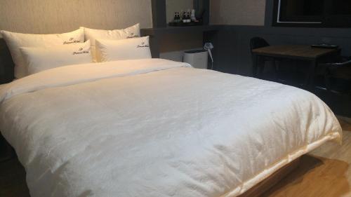 釜山普林斯汽车旅馆的一张白色大床,配有白色床单和枕头
