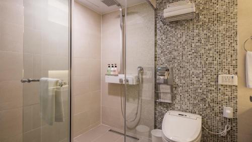 首尔First Stay Hotel的一间带卫生间和玻璃淋浴间的浴室