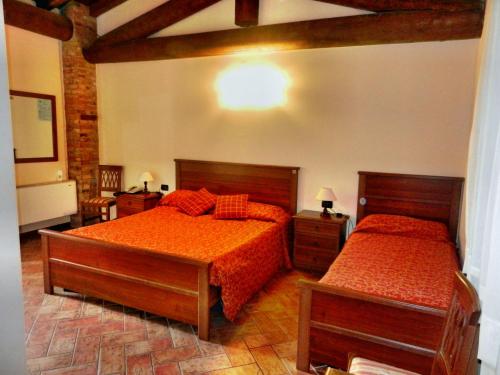 bedizzoleAgriturismo SANGALLO的一间卧室配有两张带橙色床单和木地板的床。
