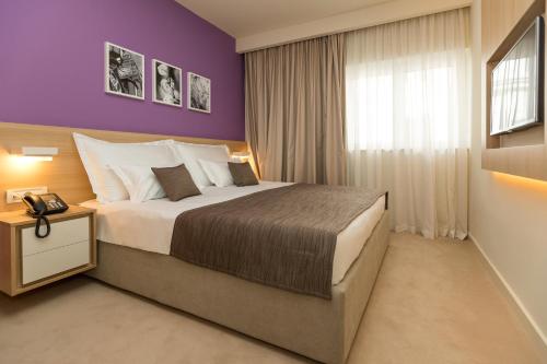 茨里克韦尼察Hotel Crikvenica的一间卧室设有一张紫色墙壁的大床