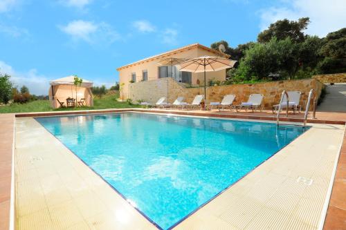 马鲁拉斯Kivotos Villa的一个带椅子的游泳池和一个背景房子