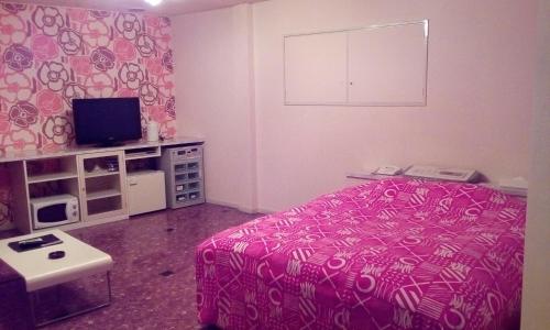 长崎茶时间酒店（情趣酒店）的一间卧室配有粉红色的床和电视