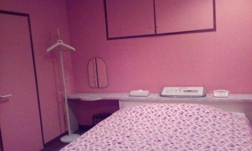 长崎茶时间酒店（情趣酒店）的卧室设有粉红色的墙壁、一张床和一张书桌