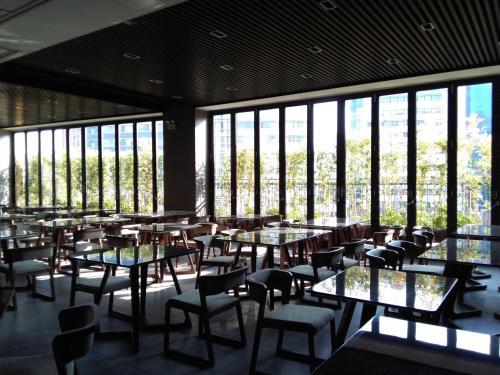 广州广州南国会·1站酒店的餐厅设有桌椅和大窗户。