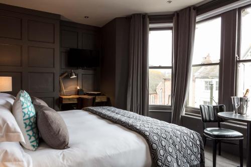 贝克斯希尔The Driftwood Bexhill的酒店客房设有一张床、一张书桌和窗户。