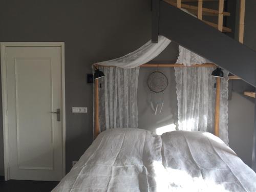 CothenBoerengastenverblijf De Kromme Rijn的一间卧室配有一张带天蓬的床和墙上的时钟