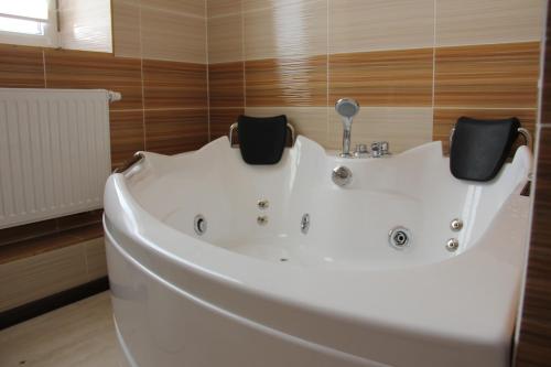 DobrovlyanyMishyN-City Hotel的浴室设有白色浴缸,拥有木墙