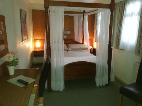 圣赫利尔泽西莫宁顿酒店的一间卧室配有一张带白色窗帘的四柱床
