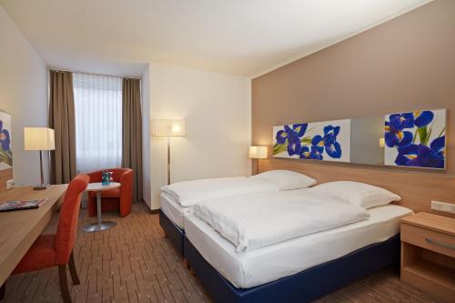 下恩豪森尼登豪森威斯巴登H+酒店的酒店客房设有一张大床、一张书桌和一张书桌。