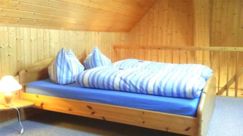 BellinFerienhaus Bellin VORP 2501的木质客房的一张床位,配有蓝色床单和枕头