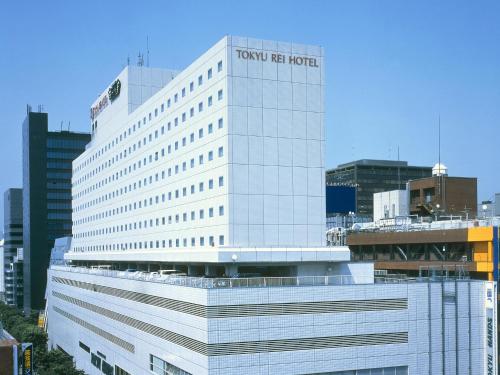 吹田新大阪江坂东急REI酒店的一座高大的白色建筑,与处女美国酒店