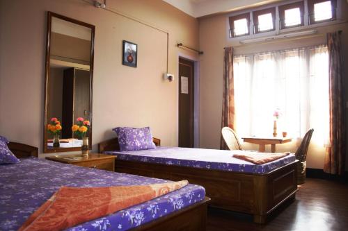 古瓦哈提Eagle Nest Home Stay的一间卧室设有两张床、一张桌子和一个窗口