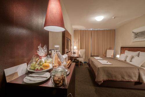 布拉迪斯拉发布拉迪斯拉发高级商务酒店的一间酒店客房,配有一张床和一张桌子上的水果盘