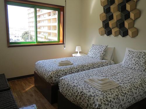 马托西纽什Porto 1 Bedroom Beach Apartment的一间卧室设有两张床和窗户。