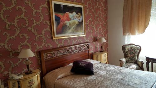 亚历山德里亚Hotel Royal的卧室配有一张床,墙上挂有绘画作品