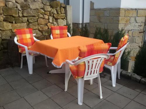 RathmannsdorfFerienwohnung Mey的桌子和四把椅子,上面有橙色毯子