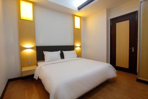 米里Imperial Suites Miri , Diamond Tower的一张大白色的床,位于一个有门的房间