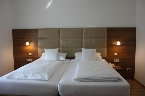 莱茵费尔登Hotel Rheinbrücke的一间卧室配有两张带白色床单和灯具的床。