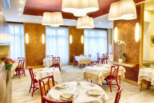 穆兰Hotel Restaurant Le Parc的餐厅设有白色的桌椅和窗户。