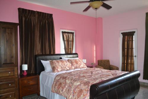 PiarcoMontecristo Inn的卧室设有粉红色的墙壁、一张床和吊扇。