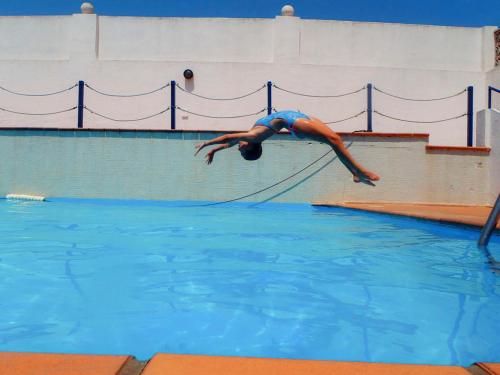 塔里法Apartamento con terraza的跳进游泳池的男人