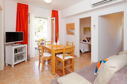波尔Apartments Villa Adria Bol的客厅配有桌子、电视和沙发。