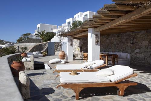 奥诺斯Beachfront Mykonos Guest House的一座庭院,庭院内设有白色的躺椅和桌子,并建有建筑