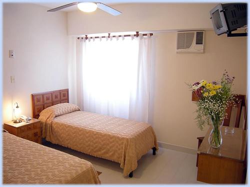 圣罗莎Hotel Lihuel Calel的一间卧室设有两张床和一扇花瓶的窗户。