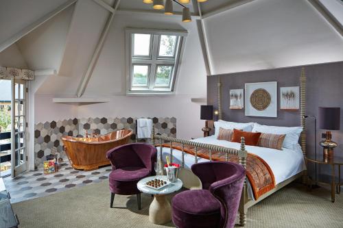 巴格肖特Pennyhill Park Hotel and Spa的一间卧室配有一张床和两张紫色椅子